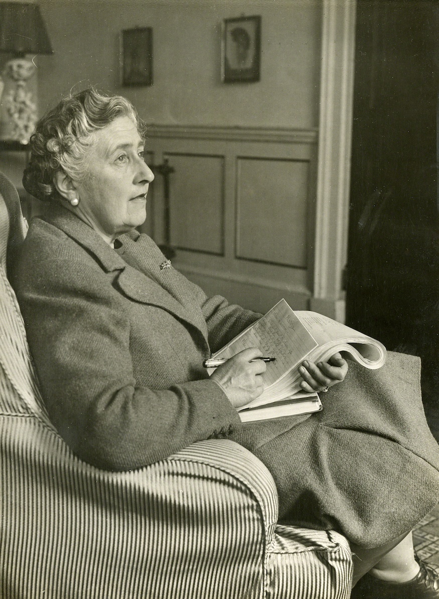 Agatha Christie sitting with newspaper making notes