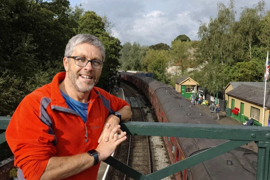 British crime fiction author Philip Swan standing on a bridge above an old train