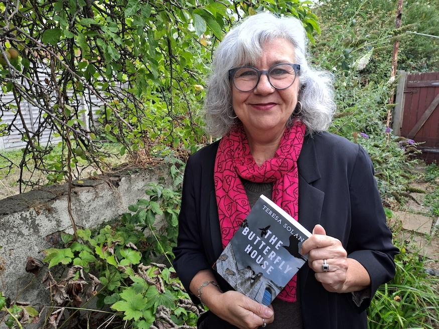 Teresa Solana holding a copy of her book The Butterfly House